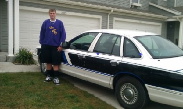 Picture of Liam standing next to the car after parking in the grass, so proud.